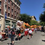 An Asian dragon puppet is being paraded on the streets of the Chinatown-International District on a sunny day.