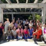 Group of KIND staff posing outside and smiling on a sunny day.